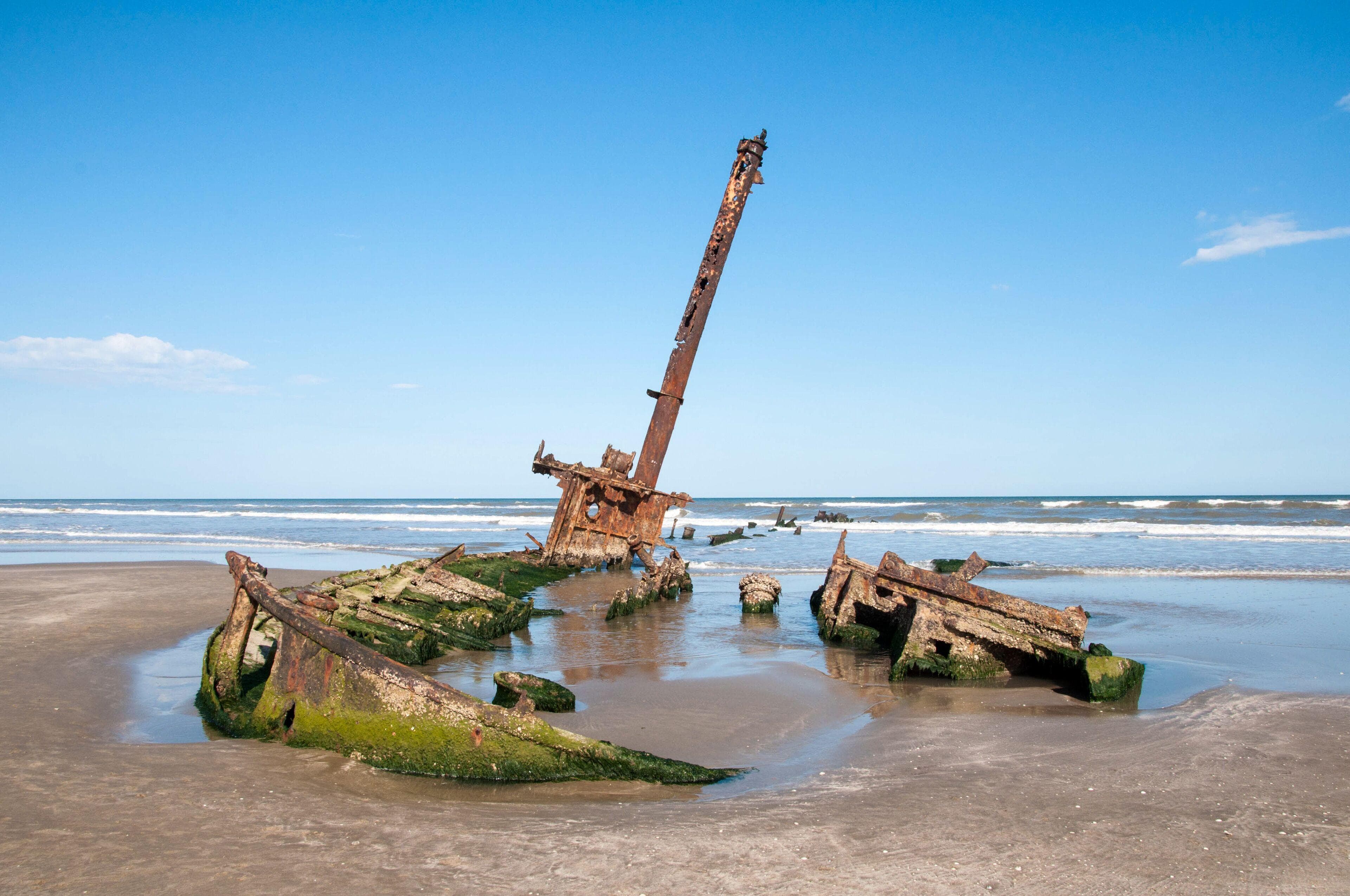 Estrutura enferrujada do Navio Altair, encalhado na areia da Praia do Cassino, próximo ao mar.